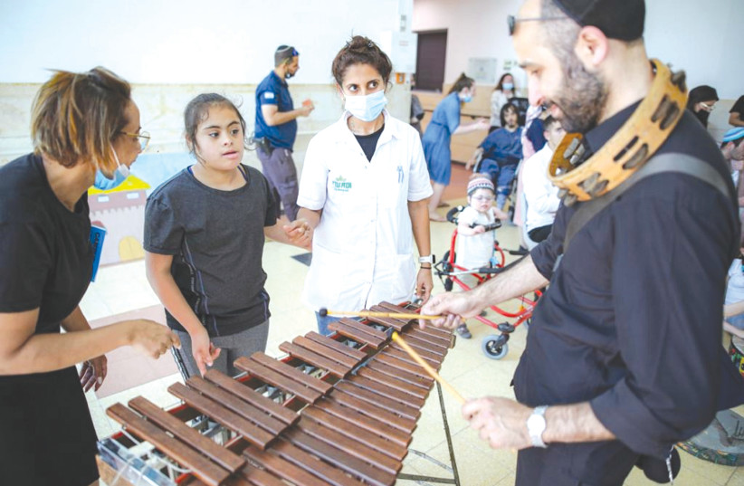  A MUSICIAN from the Israel Philharmonic Orchestra, which had come for a benefit concert, plays with a child at Adi Negev-Nahalat Eran (photo credit: ROTEM LAHAV)