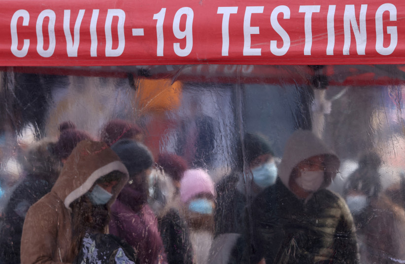  People queue to be tested for COVID-19 in Times Square, as the Omicron coronavirus variant continues to spread in Manhattan, New York City, US, December 20, 2021. (photo credit: REUTERS/ANDREW KELLY TPX IMAGES OF THE DAY)