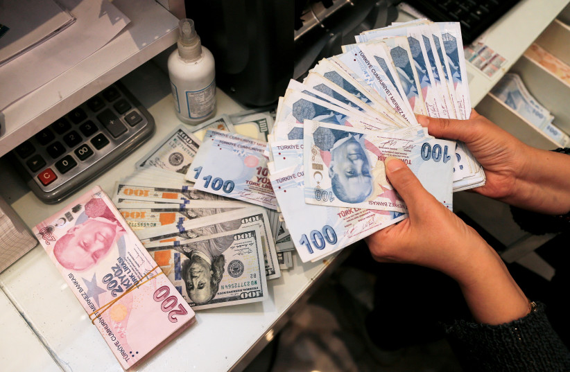 A money changer holds Turkish lira banknotes at a currency exchange office in Ankara, Turkey October 12, 2021.  (credit: REUTERS/CAGLA GURDOGAN)
