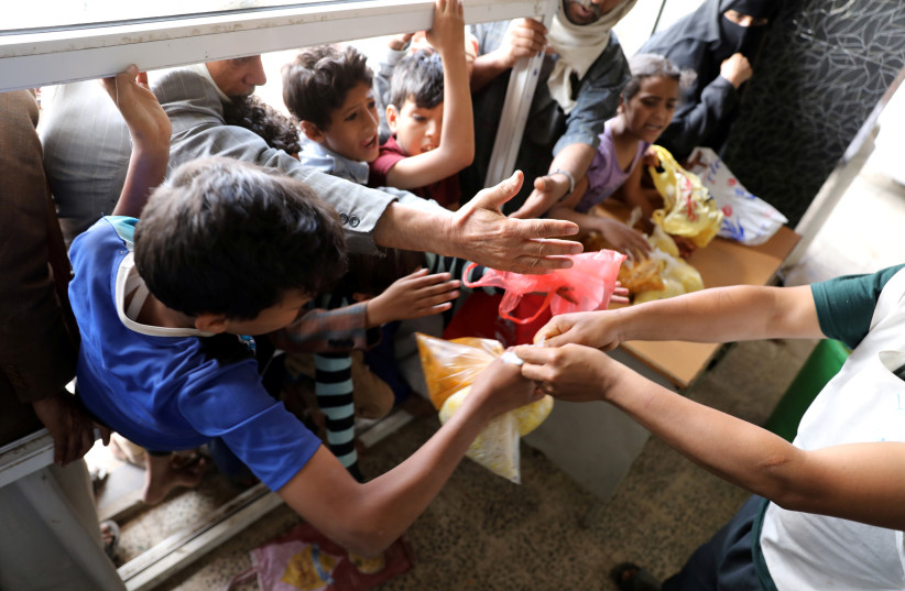  People crowd to get food rations from a charity kitchen in Sanaa, Yemen July 20, 2020. Picture taken July 20, 2020. (credit: REUTERS/KHALED ABDULLAH)