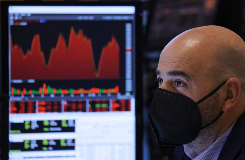  A trader in a face mask works on the trading floor at the New York Stock Exchange (NYSE) as the Omicron coronavirus variant continues to spread in Manhattan, New York City, US, December 20, 2021. (photo credit: REUTERS/ANDREW KELLY)