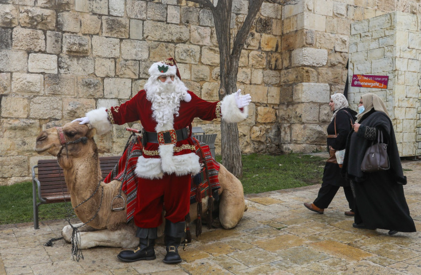  Issa Kassissieh, dressed as Santa Claus, is seen with a camel in Jerusalem's Old City, on December 23, 2021. (credit: MARC ISRAEL SELLEM/THE JERUSALEM POST)