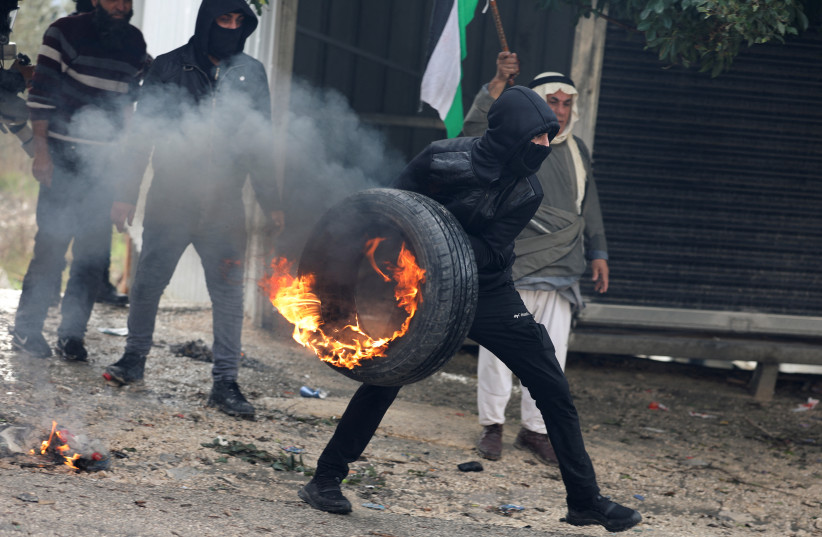   A Palestinian demonstrator holds a burning tire during a protest against Jewish settlements, in Burqa village, in the West Bank December 23, 2021. (credit: REUTERS/RANEEN SAWAFTA)