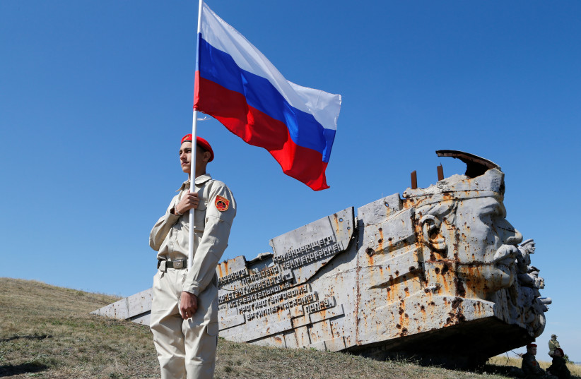 An activist holds Russia's national flag, during a rally at the war memorial complex Savur-Mohyla, damaged in the recent fighting with Ukraine's government forces,marking the 78th anniversary of the liberation of the Donbas region,Ukraine September 8, 2021. (photo credit: REUTERS/ALEXANDER ERMOCHENKO)