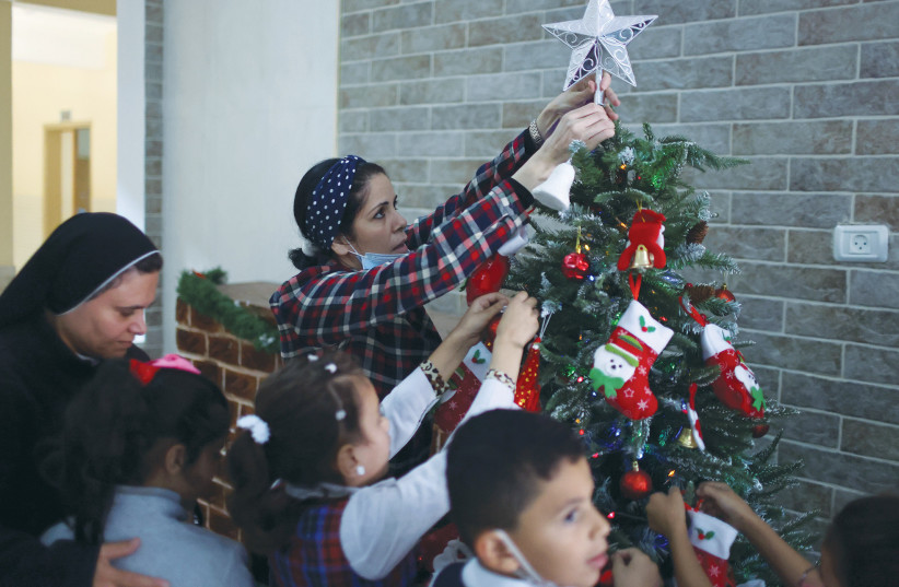  A TEACHER DECORATES a Christmas tree with students at Rosary Sisters’ School in Gaza City, last month. (photo credit: MOHAMMED SALEM/REUTERS)
