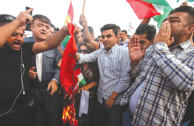  IRAQI KURDS burn the Turkish flag during a demonstration outside the UN building in Erbil in protest of Turkey’s incursion in Syria in October 2019. (photo credit: AZAD LASHKARI/REUTERS)