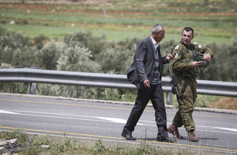  Head of the Sinjil village speaks an Israeli soldier at the scene where a Palestinian attacker stabbed two Israeli soldiers earlier today near Maaleh Nevona in the Binyamin area of the West Bank, on April 8, 2015. (photo credit: HADAS PARUSH/FLASH90)