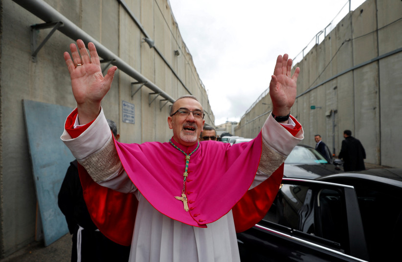  Pierbattista Pizzaballa, the Latin Patriarch of Jerusalem, waves near the Israeli barrier as he arrives through an Israeli checkpoint to attend Christmas celebrations in Bethlehem, in the West Bank December 24, 2021. (photo credit: MOHAMAD TOROKMAN/REUTERS)