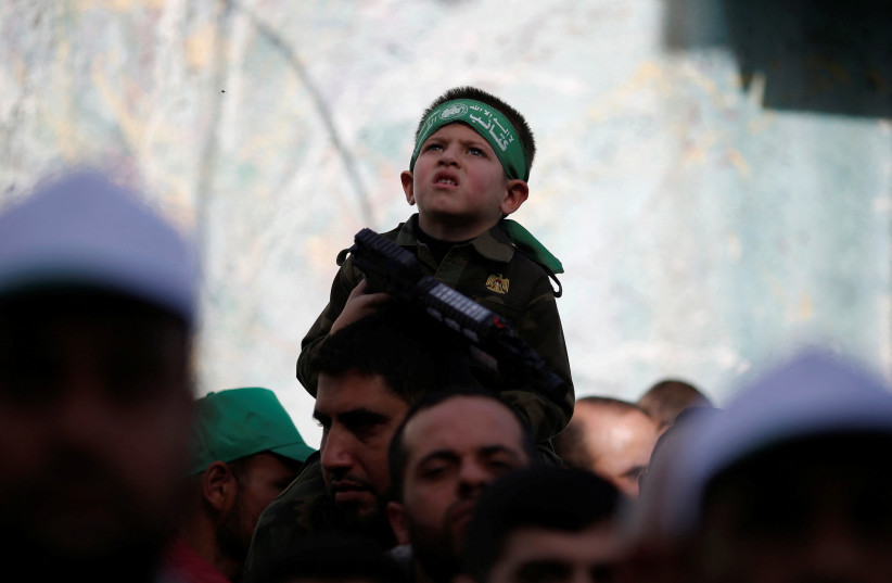  A boy holds a toy weapon as Palestinians take part in a rally marking the 34th anniversary of Hamas' founding, in the northern Gaza Strip December 10, 2021.  (photo credit: MOHAMMED SALEM/REUTERS)