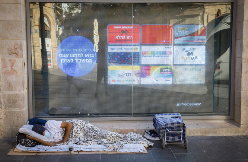  A homeless person sleeps in the street on Jaffa Street in downtown Jerusalem on September 23, 2020, during a nationwide lockdown (photo credit: NATI SHOHAT/FLASH90)