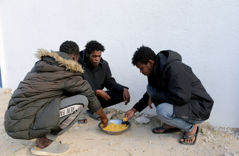  Somali migrant Abdul Razzaq Yassin eat with other migrants at the headquarters of immigration in Benghazi, Libya December 5, 2020.  (credit: REUTERS/ESAM OMRAN AL-FETORI)