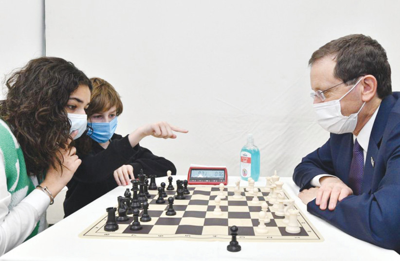  PRESIDENT ISAAC HERZOG pitted against junior chess players Sahar Mansour and Adam Pels.  (photo credit: HAIM ZACH/GPO)