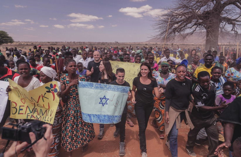  The Tikkun Olam state: A bar mitzvah boy waves the Israeli flag as he marches after raising funds for a solar-water pumping system in the African village of Sasajila, Tanzania (credit: INNOVATION:AFRICA)