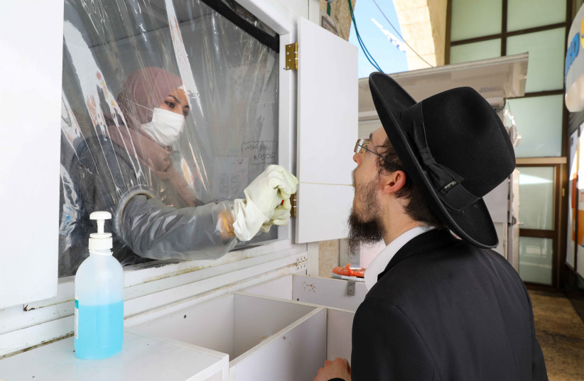 A haredi man receives a corona test from a Palestinian health worker. (credit: MARC ISRAEL SELLEM)