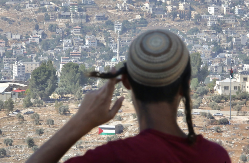  A young man at the settlement of Evyatar looks out at a neighboring Palestinian village. (photo credit: MARC ISRAEL SELLEM)