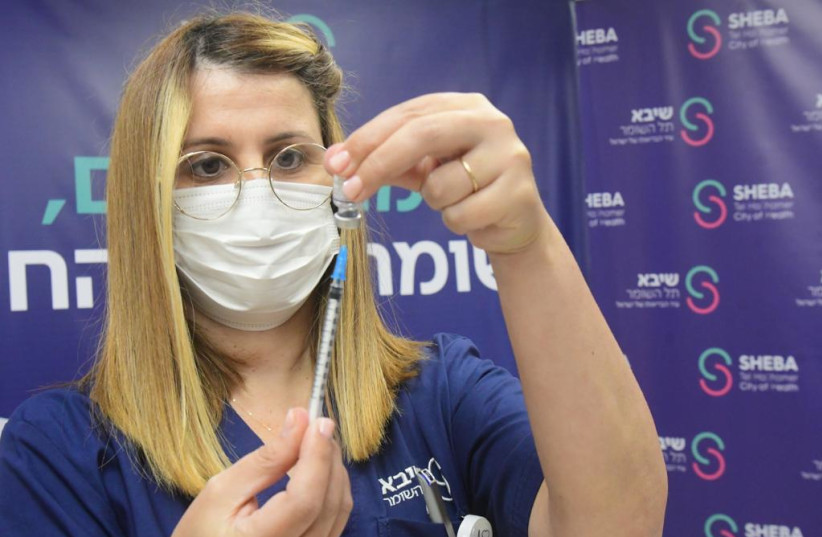  A nurse prepares to administer a fourth booster Pfizer COVID-19 vaccine to a person with an implanted heart. (photo credit: AVSHALOM SASSONI/MAARIV)