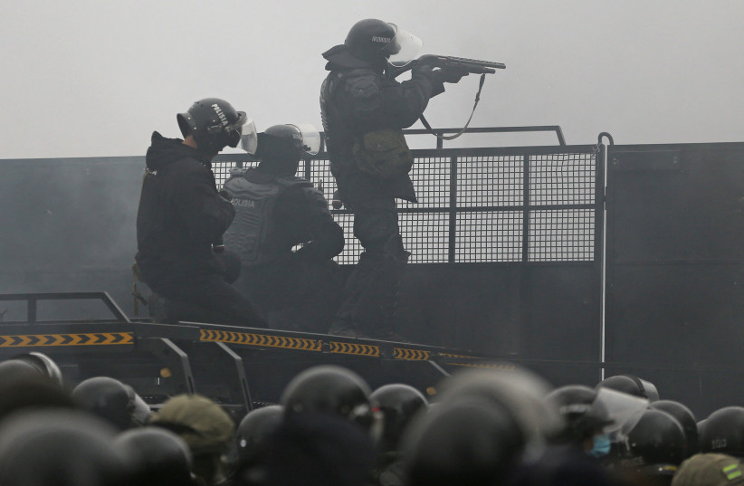  Kazakh law enforcement officers are seen on a barricade during a protest triggered by fuel price increase in Almaty, Kazakhstan January 5, 2022. (photo credit: REUTERS/PAVEL MIKHEYEV)