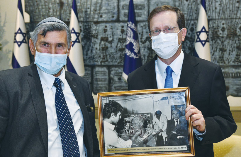  SCULPTOR SHMUEL BEN AMI presents President Isaac Herzog with a photograph of his father, president Chaim Herzog, posing for a bust created by Ben Ami. (photo credit: HAIM ZACH/GPO)