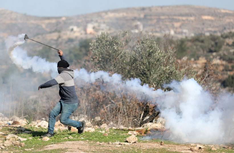  Un manifestant palestinien utilise une fronde lors d'une manifestation contre les colonies israéliennes à Beita, en Cisjordanie, le 7 janvier 2022. (Crédit : REUTERS/RANEEN SAWAFTA)