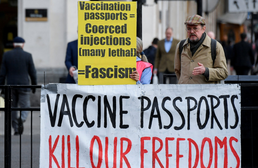  A person holds an anti-vaccination sign near the Houses of Parliament, as the spread of the coronavirus disease (COVID-19) continues in London, Britain, December 14, 2021. (credit: REUTERS/TOBY MELVILLE)