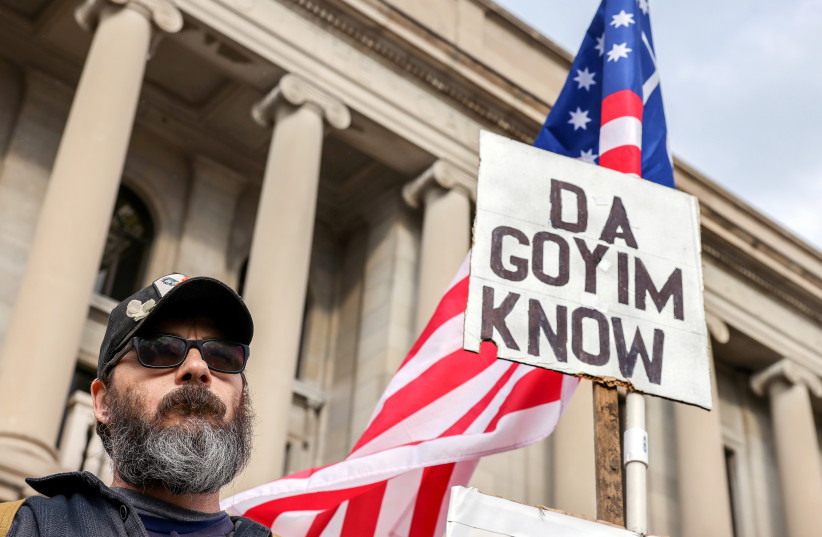  A protestor carries a white supremacist and antisemitic sign outside the Kenosha County Courthouse on the second day of jury deliberations in the Kyle Rittenhouse trial, in Kenosha, Wisconsin, US, November 17, 2021.  (photo credit: REUTERS/EVELYN HOCKSTEIN)