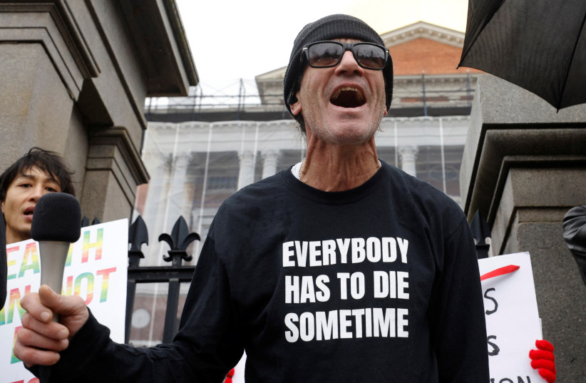  Pat Mendoza, co-owner of the restaurant Monica's Trattoria, wears a shirt reading ''Everybody has to die sometime'' while speaking to the crowd at a protest against coronavirus disease (COVID-19) vaccine mandates in Boston, Massachusetts, US, January 5, 2022.  (credit: REUTERS/BRIAN SNYDER)