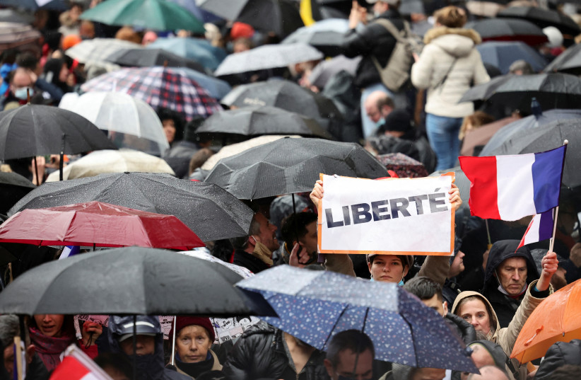  A person holds a sign that reads "Freedom" as people attend a demonstration to protest against a bill that would transform France's current coronavirus disease (COVID-19) health pass into a ''vaccine pass'', in Paris, France, January 8, 2022. (photo credit: REUTERS/SARAH MEYSSONNIER)