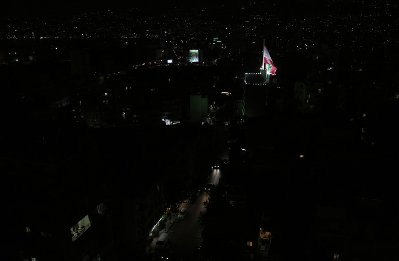  A Lebanese flag flutters near unlit residential buildings during a partial blackout in Beirut, Lebanon August 11, 2021 (photo credit: REUTERS/ISSAM ABDALLAH)