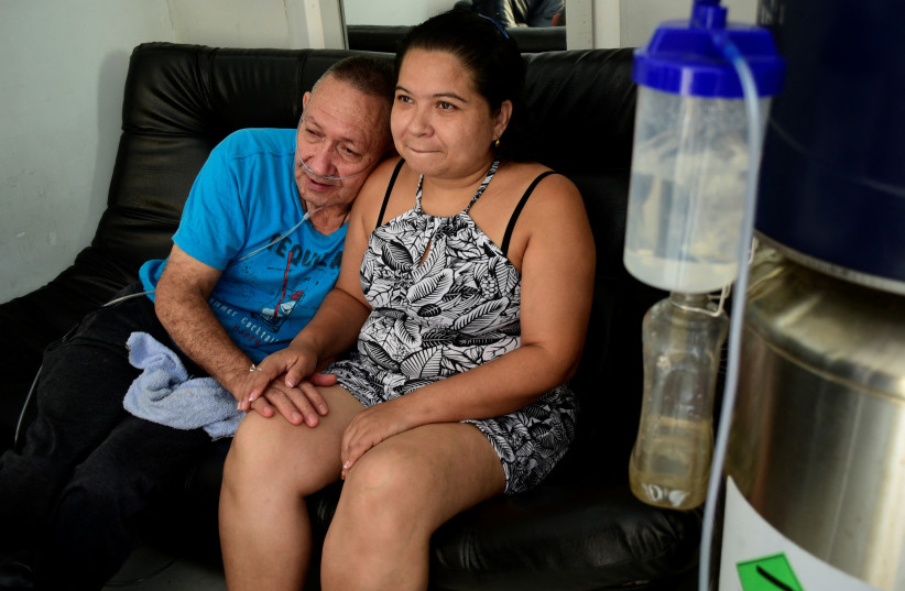 Victor Escobar, 60, who suffered from an end-stage chronic obstructive pulmonary disease and became the first person in Colombia to undergo euthanasia for a non-terminal disease, leans on the shoulder of his wife Diana Nieto at their home in Cali, Colombia, October 19, 2021. (photo credit: REUTERS/EDWIN RODRIGUEZ PIPICANO)