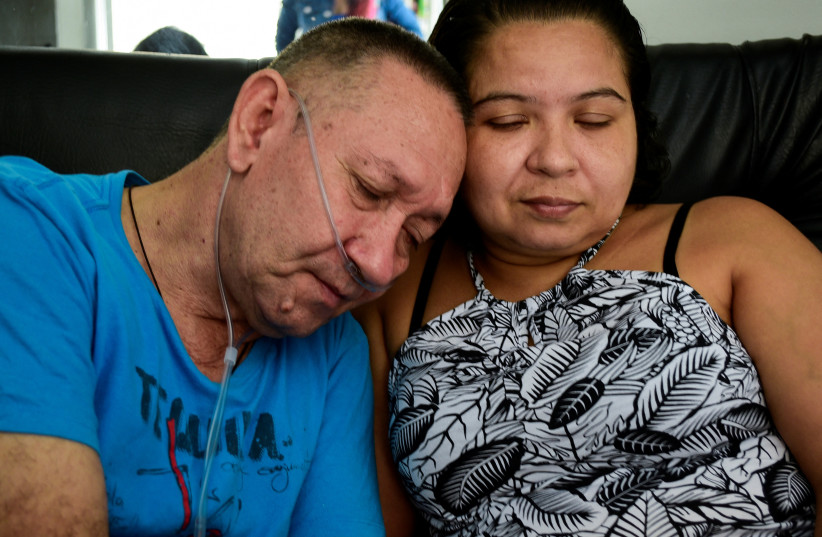 Victor Escobar, 60, who suffered from an end-stage chronic obstructive pulmonary disease and became the first person in Colombia to undergo euthanasia for a non-terminal disease, leans on the shoulder of his wife Diana Nieto at their home in Cali, Colombia, October 19, 2021. (credit: REUTERS/EDWIN RODRIGUEZ PIPICANO)