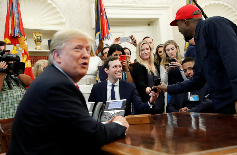 Rapper Kanye West shows a photo on his mobile phone to White House senior adviser Jared Kushner during a meeting with US President Donald Trump to discuss criminal justice reform at the White House in Washington, US, October 11, 2018. (photo credit: REUTERS/KEVIN LAMARQUE)