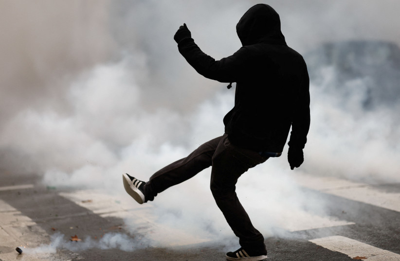  A protestor kicks a tear gas canister during a demonstration to protest against a bill that would transform France's current coronavirus disease (COVID-19) health pass into a "vaccine pass", in Nantes, France, January 8, 2022.  (photo credit: REUTERS/STEPHANE MAHE)