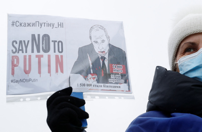  Demonstrators hold placards during a protest against Russian President Vladimir Putin's policies, in Kyiv, Ukraine January 9, 2022. (credit: REUTERS/VALENTYN OGIRENKO)