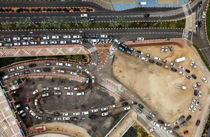 People queue in their cars to be tested for coronavirus disease (COVID-19) as the country faces a surge in Omicron variant infections in Ashdod, Israel January 3, 2022. Picture taken with a drone.  (photo credit: REUTERS/AMIR COHEN)