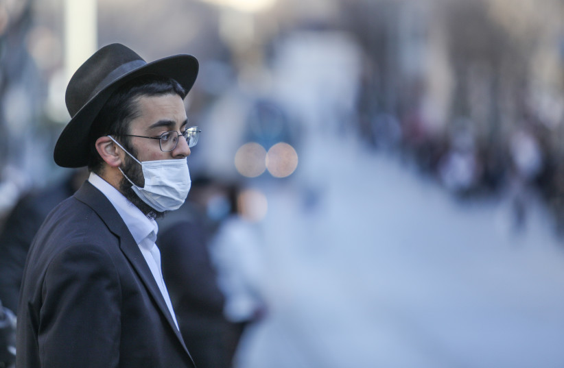  Illustrative photo of a man walking with a mask in Jerusalem, January 10 2021. (photo credit: MARC ISRAEL SELLEM/THE JERUSALEM POST)