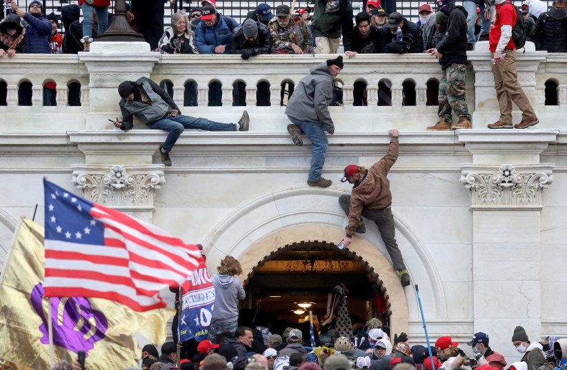  A mob of supporters of U.S. President Donald Trump fight with members of law enforcement at a door they broke open as they storm the US Capitol Building in Washington, US, January 6, 2021.  (photo credit: LEAH MILLIS/REUTERS)