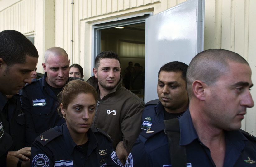  Palestinian Amjad Awad (back, 3rd R) is escorted by Israeli prison guards after his sentencing at an Israeli military court in the West Bank city of Jenin January 16, 2012.  (credit: NIR ELIAS/REUTERS)