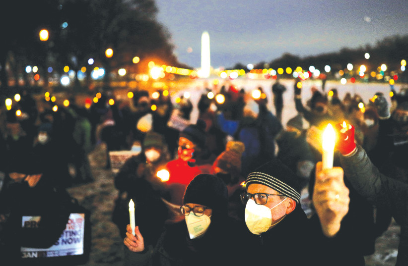 People hold candles at a vigil at the National Mall in Washington last Thursday as they mark the first anniversary of the January 6, 2021 Capitol insurrection that was carried out by supporters of former president Donald Trump. (credit: TOM BRENNER/REUTERS)