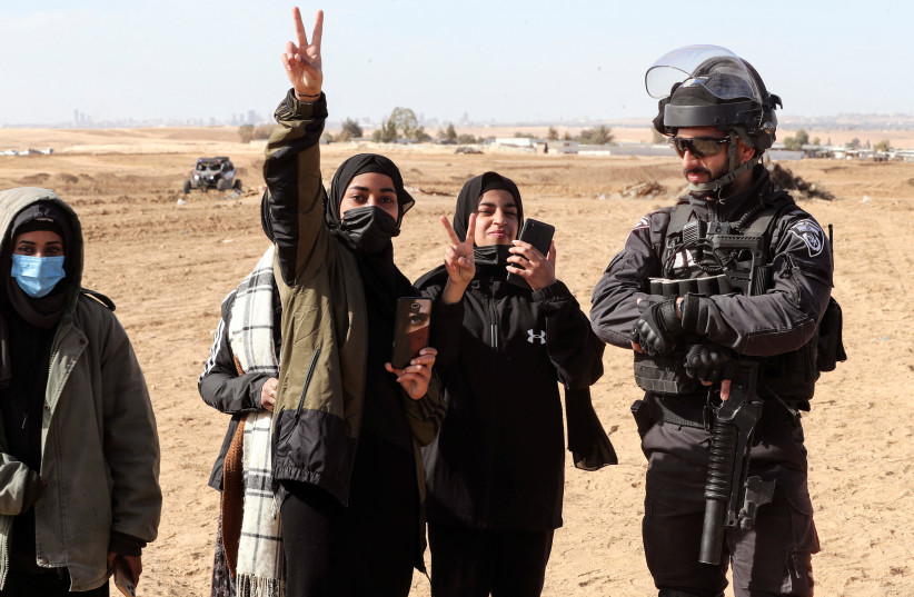  Bedouin women gesture as they stand by an Israeli policeman during a protest against forestation at the Negev desert village of Sawe al-Atrash, southern Israel (photo credit: REUTERS/AMMAR AWAD)
