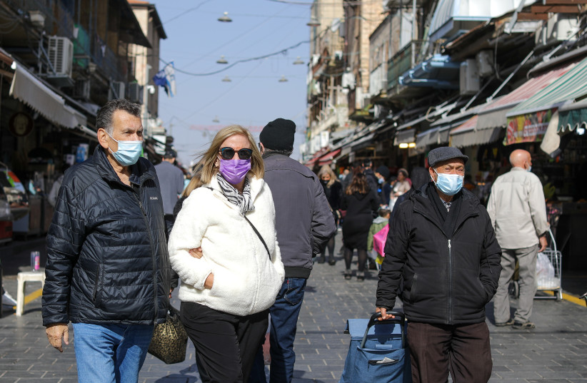  Israelis, some wearing masks, are seen walking in Jerusalem's Machane Yehuda market on January 13, 2022 (photo credit: MARC ISRAEL SELLEM/THE JERUSALEM POST)