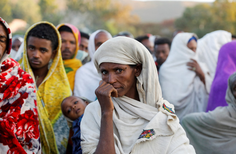 A woman stands in line to receive food donations, at the Tsehaye primary school, which was turned into a temporary shelter for people displaced by conflict, in the town of Shire, Tigray region, Ethiopia, March 15, 2021. (photo credit: REUTERS/BAZ RATNER/FILE PHOTO)