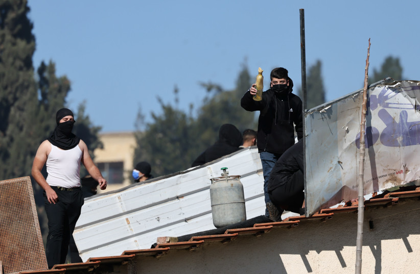  Palestinians with gas cylinders stand on a rooftop of a house being evacuated by Israeli special forces in the East Jerusalem neighborhood of Sheikh Jarrah. January 17, 2022. (credit: YONATAN SINDEL/FLASH90)