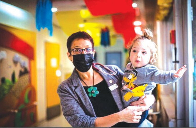  THE WRITER poses with a child who is a patient at ALYN Hospital. (photo credit: OREN BEN HAKOON)