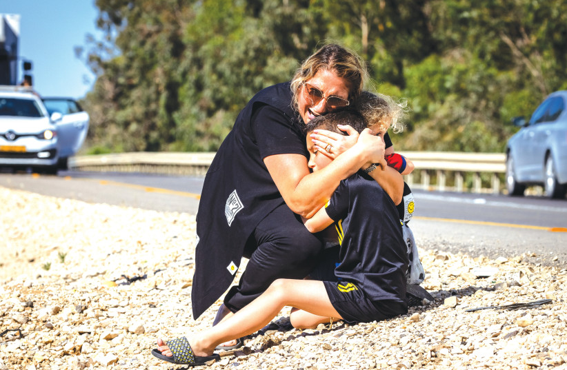  A WOMAN and child take cover on a road between Ashkelon and Sderot in May, 2021, as a siren sounds, warning of incoming rockets from the Gaza Strip. (photo credit: OLIVIER FITOUSSI/FLASH90)