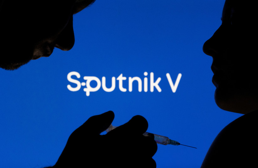 People pose with syringe with needle in front of displayed Sputnik V logo in this illustration taken, December 11, 2021. (photo credit: REUTERS/DADO RUVIC/ILLUSTRATION)