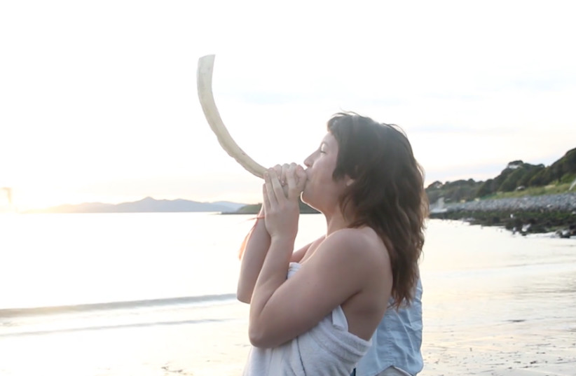  Rebekah Erev, co-founder of the Queer Mikveh Project, blows the shofar at the first QMP mikvah event at the Albany Bulb in Albany, California, in 2015. (photo credit: CHANI BOCKWINKEL VIA JTA)