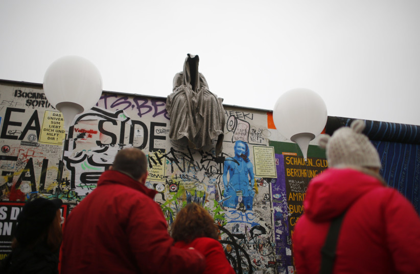 A sculpture by Austrian contemporary artist Manfred Kielnhofer sits atop a section of the former Berlin Wall next to the installation 'Lichtgrenze' (Border of Light) along the East Side Gallery, the largest remaining part of the former Berlin Wall, in Berlin, November 9, 2014. (photo credit: REUTERS/HANNIBAL HANSCHKE)