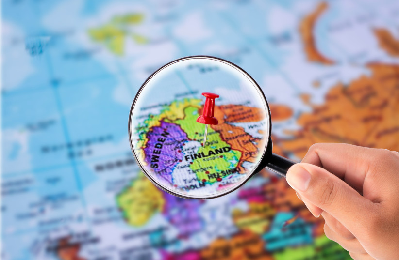  hand holding Magnifying Glass in front of map find Finland (photo credit: INGIMAGE)