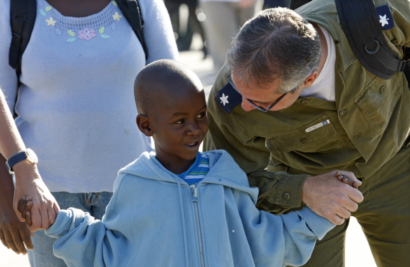  DR. YUVAL LEVY, part of an Israeli military medical team that treated earthquake victims in Haiti, holds hands with a 6-year-old Haitian boy expected to undergo heart surgery in Israel, upon their arrival from Haiti at Ben-Gurion Airport on January 28, 2010. (credit: GIL COHEN MAGEN/REUTERS)