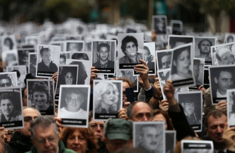  HOLDING UP images of the victims of the 1994 bombing on Argentina’s AMIA center, to mark the attack’s 25th anniversary, in Buenos Aires, July 18, 2019. (credit: AGUSTIN MARCARIAN/REUTERS)